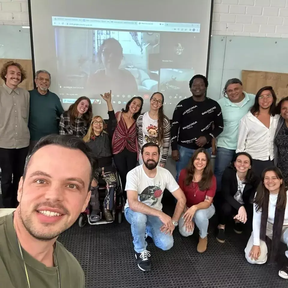Foto da turma da disciplina Educação Intercultural reunida diante do telão de uma sala de aula da UFSC, com um estudante fazendo a selfie em primeiro plano